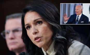 Woman speaking at press conference with warning sign