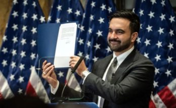 Man holding document in front of American flags
