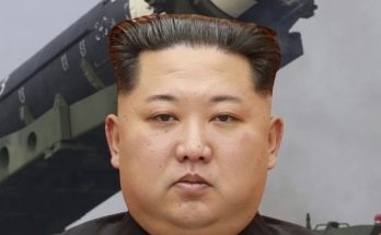 kim Jong Un stands before a large military missile launcher marked with numbers 205