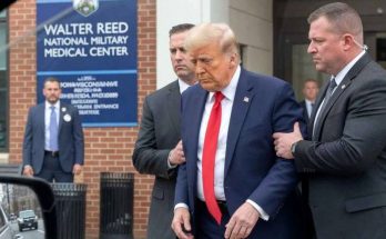 donald Trump in navy suit and red tie being escorted by Secret Service agents outside