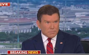 news anchor in dark suit and red striped tie delivering breaking news broadcast with