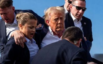 donald Trump surrounded by Secret Service agents with blood visible on his ear and face