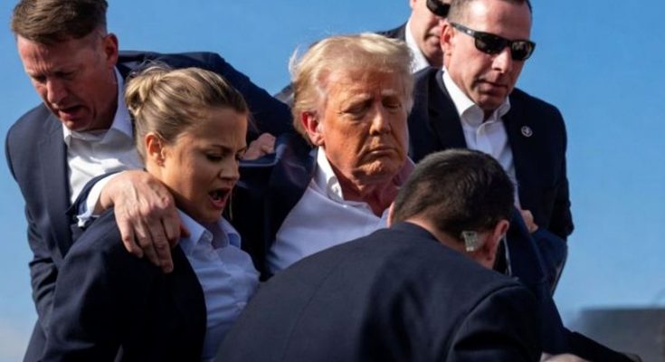 donald Trump surrounded by Secret Service agents with blood visible on his ear and face