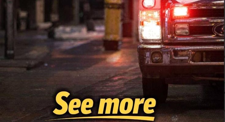 close-up of a red Ford pickup truck's front grille and headlights, parked on a wet city