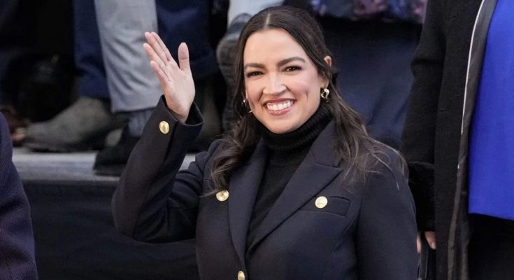 alexandria Ocasio-Cortez waves while wearing a black coat with gold buttons and black