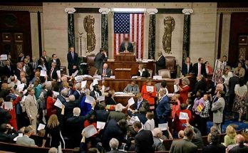 members of Congress hold papers during a protest on the House floor beneath the American