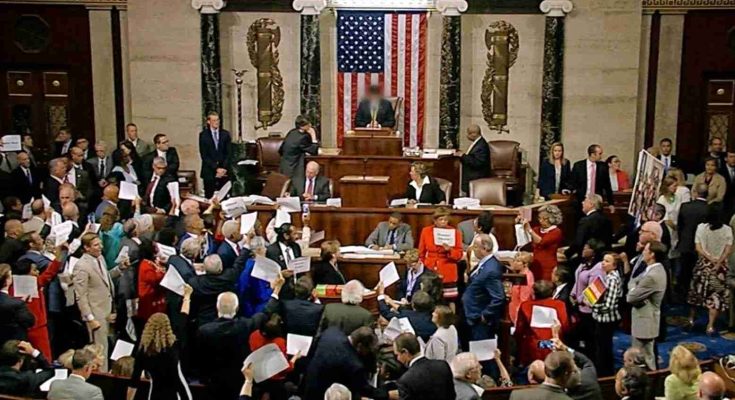 members of Congress hold papers during a protest on the House floor beneath the American