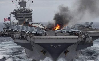 USS George H.W. Bush aircraft carrier on rough seas with visible fire and smoke eruptingv