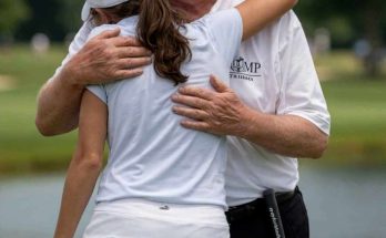 donald Trump wearing red MAGA cap hugging young woman golfer on green with golf clubs