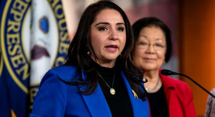 woman in blue blazer speaks at U.S. House of Representatives podium with colleague in red