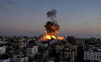 massive explosion sends fire and dark smoke rising above densely packed city buildings at