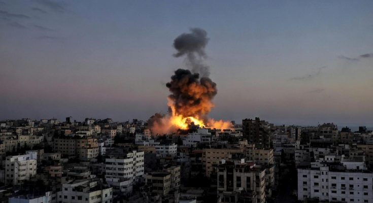 massive explosion sends fire and dark smoke rising above densely packed city buildings at