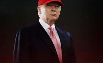 donald Trump wearing a red USA cap and pink tie with a serious expression against a dark