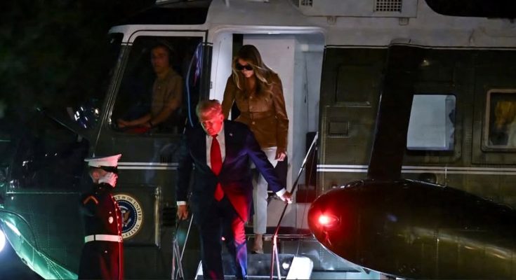 donald Trump descends Marine One stairs at night while Melania Trump follows wearing