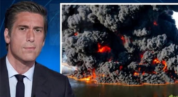 news anchor in studio with split screen showing massive industrial fire with thick black