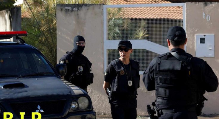 brazilian federal police officers in tactical gear stand near a black Mitsubishi patrol