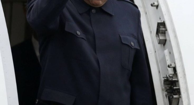 nicolás Maduro raises clenched fist while exiting aircraft doorway in dark blue uniform