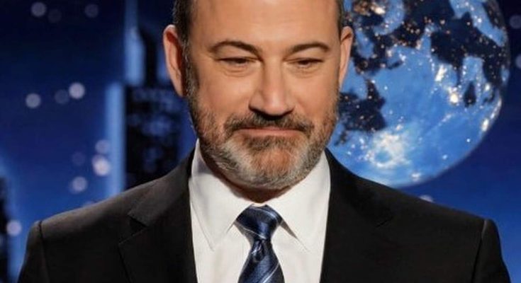 jimmy Kimmel in dark suit and striped tie against blue globe backdrop with city skyline