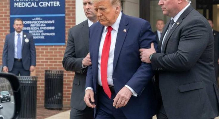 donald Trump in navy suit and red tie being escorted by Secret Service agents outside
